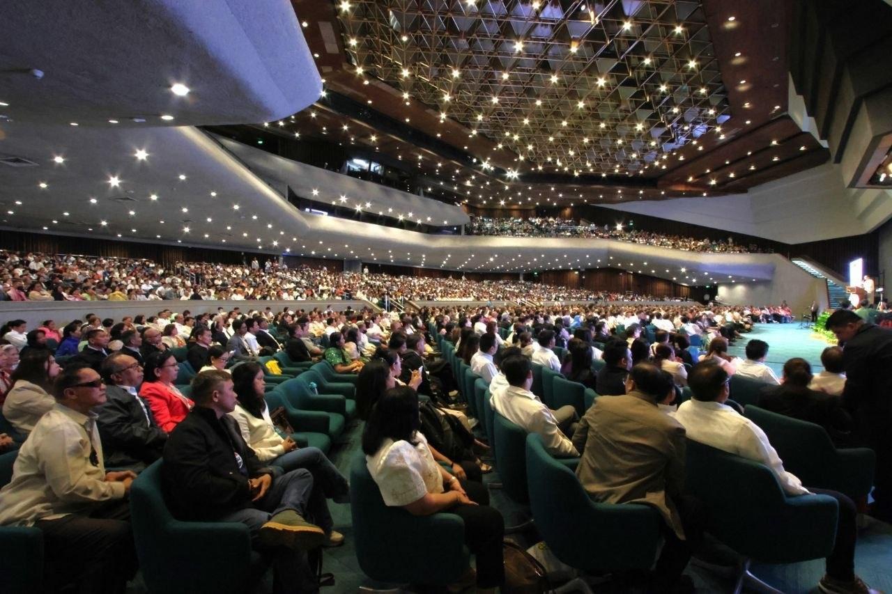 Audience seated in a large auditorium during a public gathering.